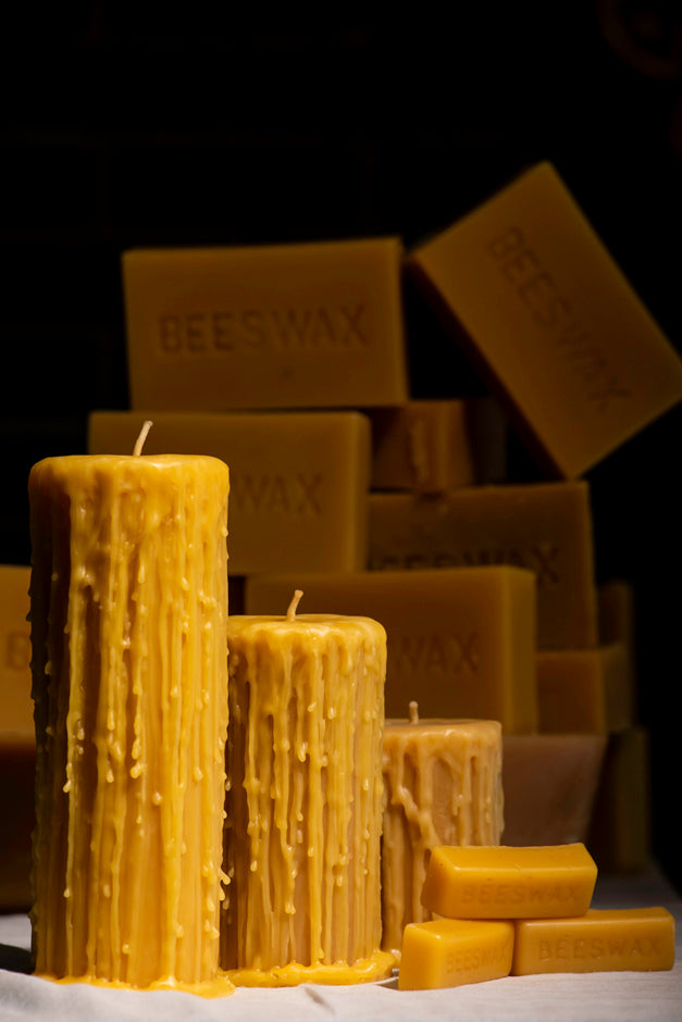 Drippy beeswax pillar candles and beeswax bars on a dark background