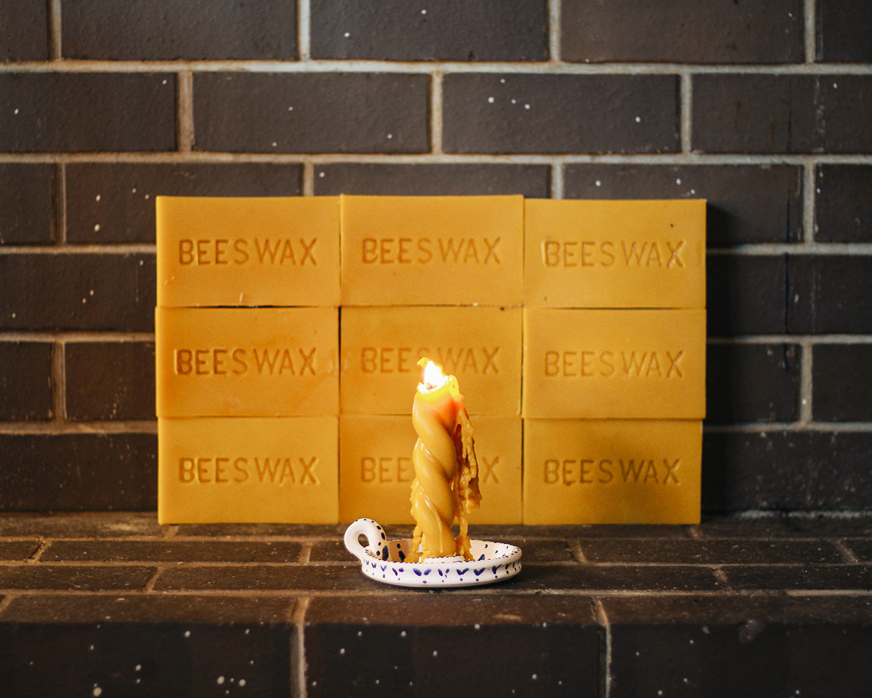 Burning twisted beeswax candle with beeswax bars in background.